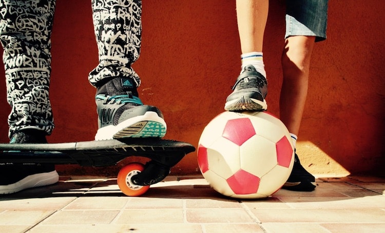kids with feet propped up on skateboard and soccer ball